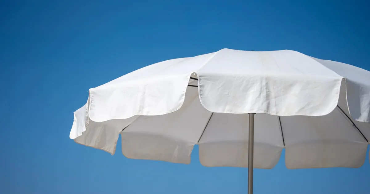 A white parasol against a clear blue sky