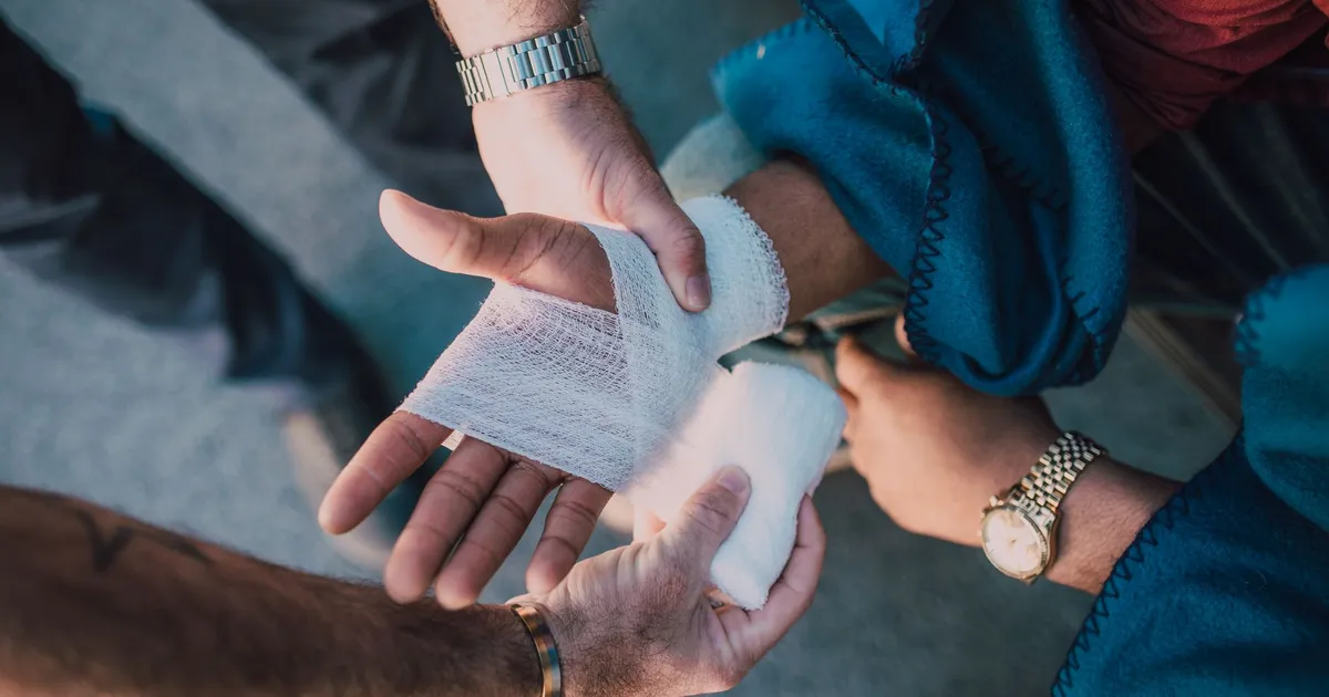 Two people bandaging an injured hand