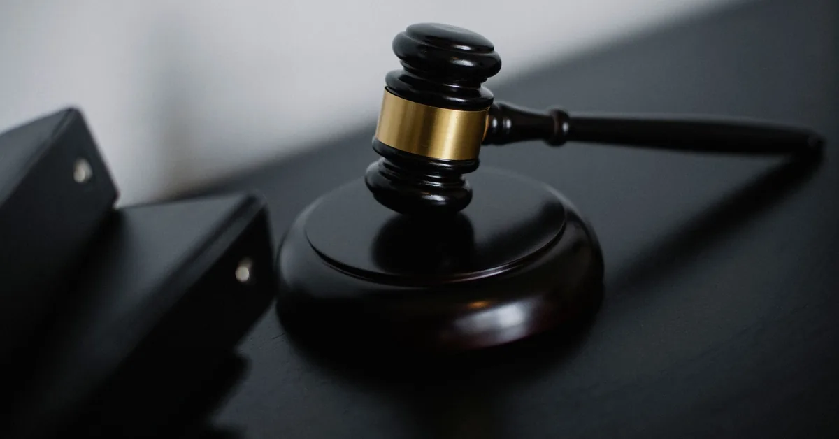 A wooden judge's gavel resting on a dark desk