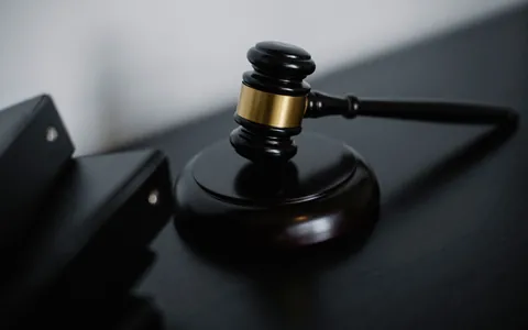 A wooden judge's gavel resting on a dark desk