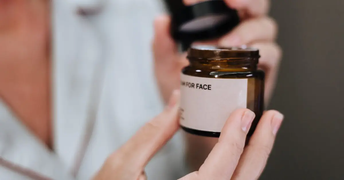 Detailed shot of hands opening a face cream jar, highlighting skincare routine