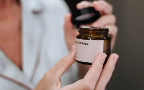 Detailed shot of hands opening a face cream jar, highlighting skincare routine