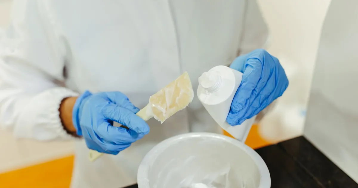 Gloved hands mixing a skincare cream in a laboratory