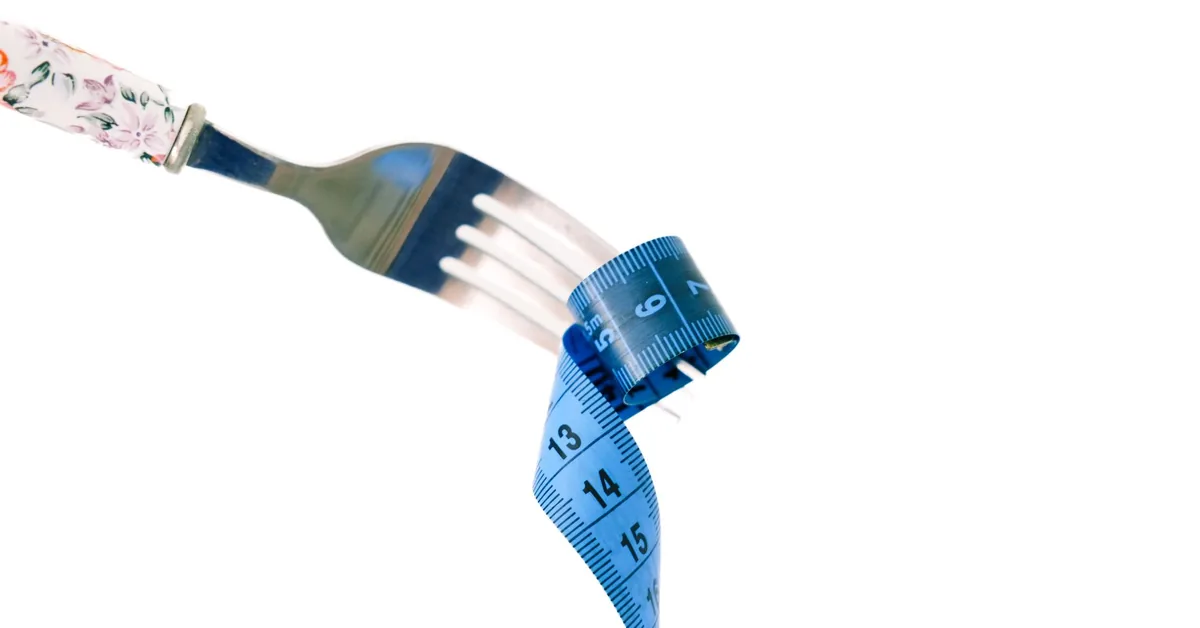 A fork wrapped in a blue measuring tape on a white plate