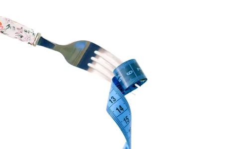 A fork wrapped in a blue measuring tape on a white plate