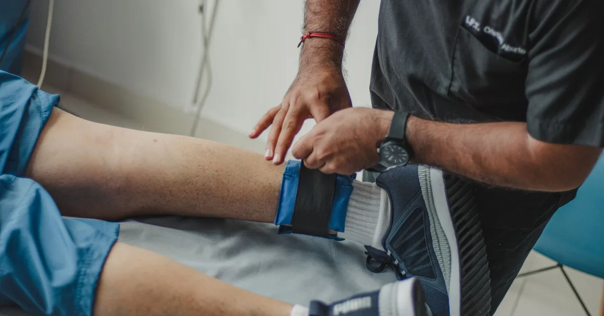 A physiotherapist applying electrode therapy to a patient's knee