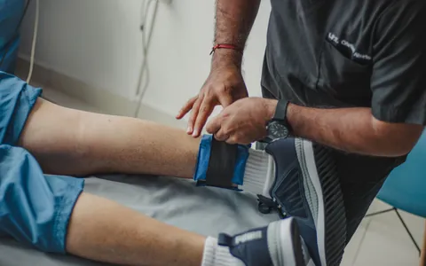 A physiotherapist applying electrode therapy to a patient's knee
