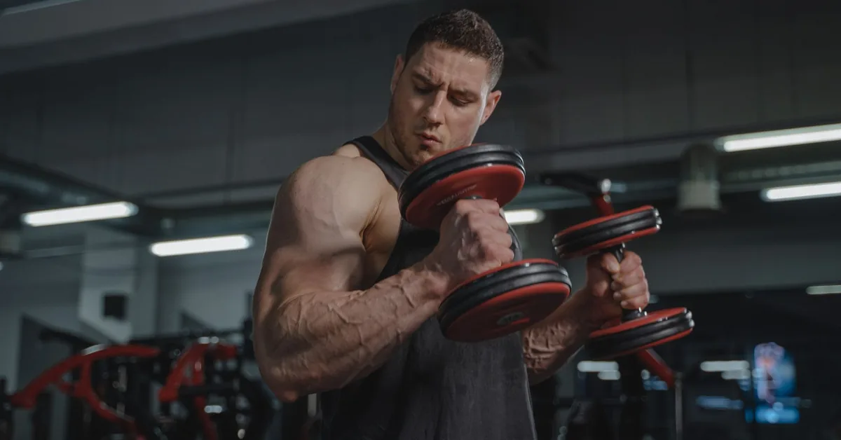 A man curling a dumbbell during a workout in a gym