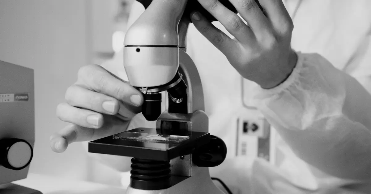 A scientist in a lab coat using a microscope for research in a laboratory setting