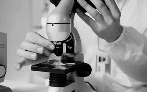 A scientist in a lab coat using a microscope for research in a laboratory setting