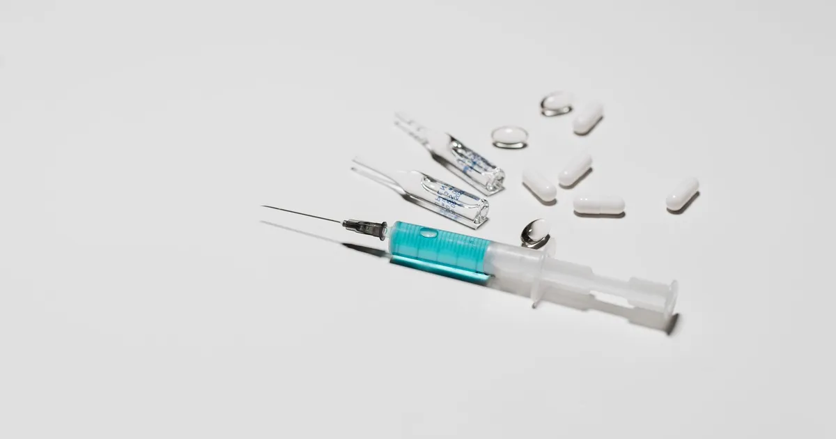 A syringe, capsules and glass ampoules lying on a white surface
