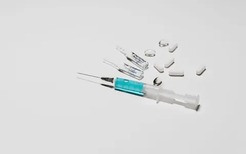 A syringe, capsules and glass ampoules lying on a white surface