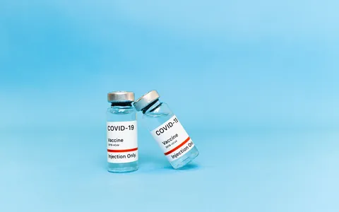 Two small glass medical vials standing on a blue background