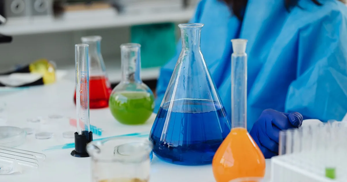 Laboratory flasks filled with coloured liquids on a bench