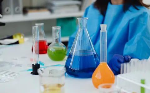 Laboratory flasks filled with coloured liquids on a bench