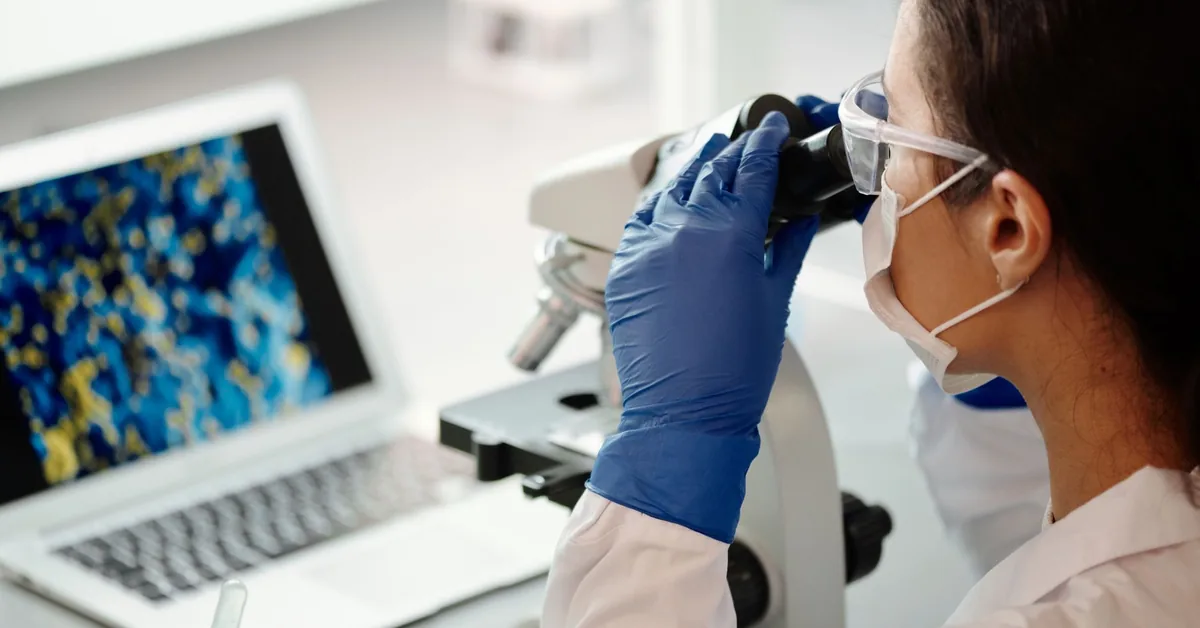 A scientist looking into a microscope in a research lab