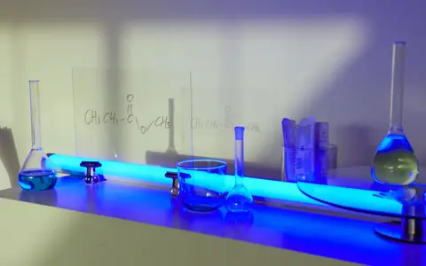 Various glass flasks and equipment in a lab with blue lighting ambiance