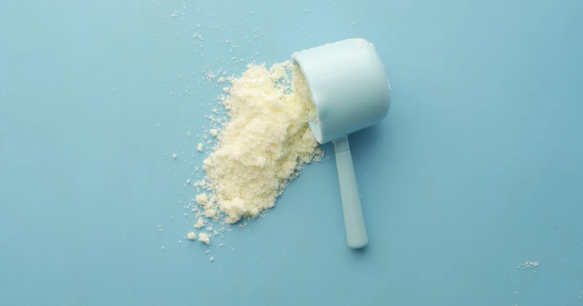 White powder spilled from a scoop on a bright blue background