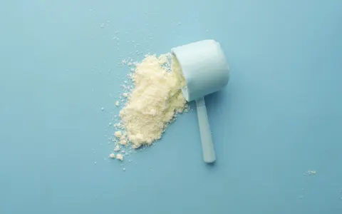 White powder spilled from a scoop on a bright blue background