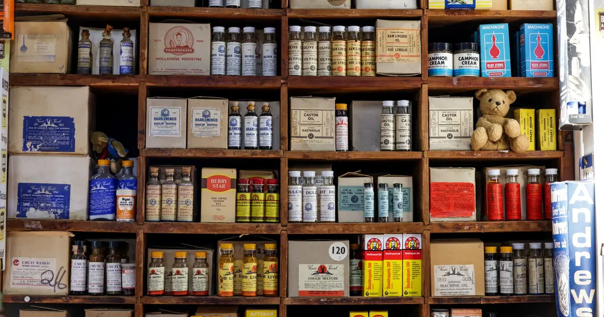 A pharmacy shelf lined with old medicine bottles and boxes