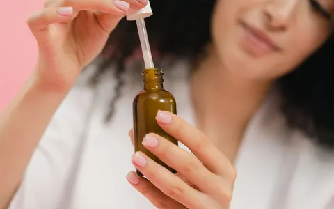 A woman holding a brown glass dropper bottle of skin serum