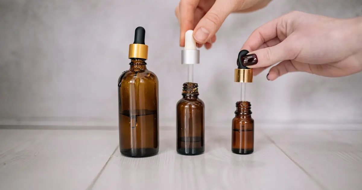 Close-up shot of hands holding brown bottles with droppers, ideal for skincare and aromatherapy themes