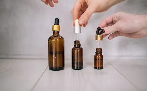 Close-up shot of hands holding brown bottles with droppers, ideal for skincare and aromatherapy themes