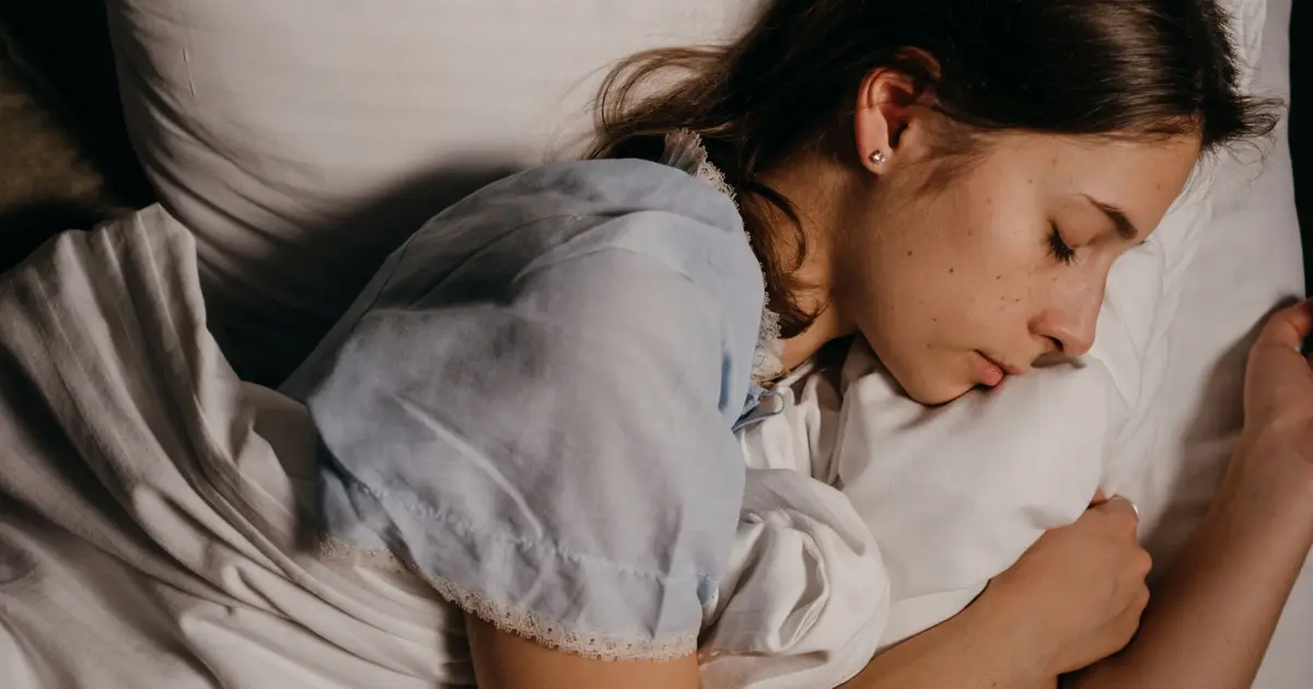A serene young woman peacefully sleeping on a white pillow indoors at night