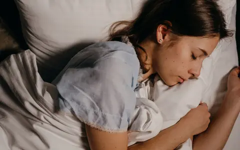 A serene young woman peacefully sleeping on a white pillow indoors at night