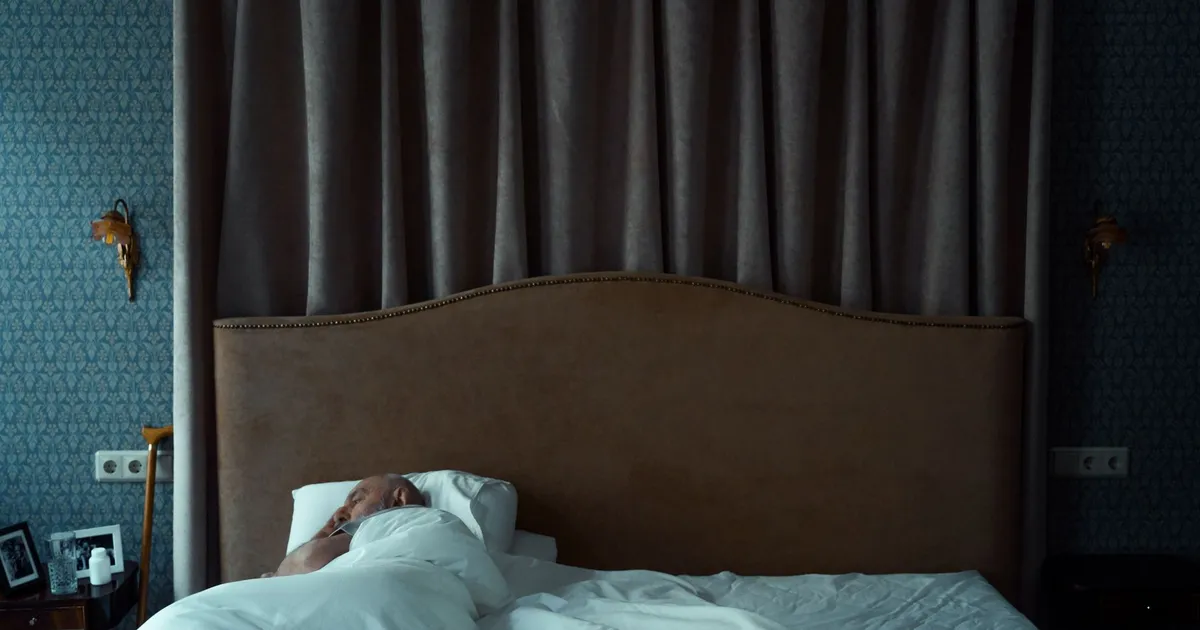 A man sleeping in a bed under a white blanket