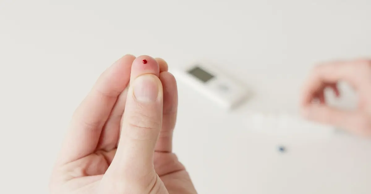 A close-up view of a hand with a blood drop, illustrating a diabetic blood sugar test