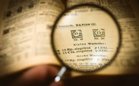 Detailed view of a book page magnified by a glass, enhancing text clarity