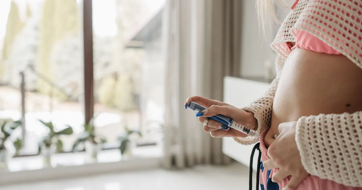 A woman injecting insulin with a pen at home