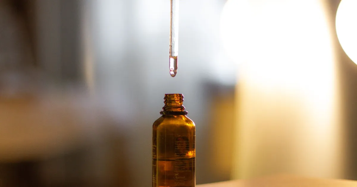 A serum dropper held above an amber glass bottle
