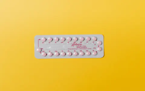 Close-up of a blister pack of pink pills on a vivid yellow background for medication concept