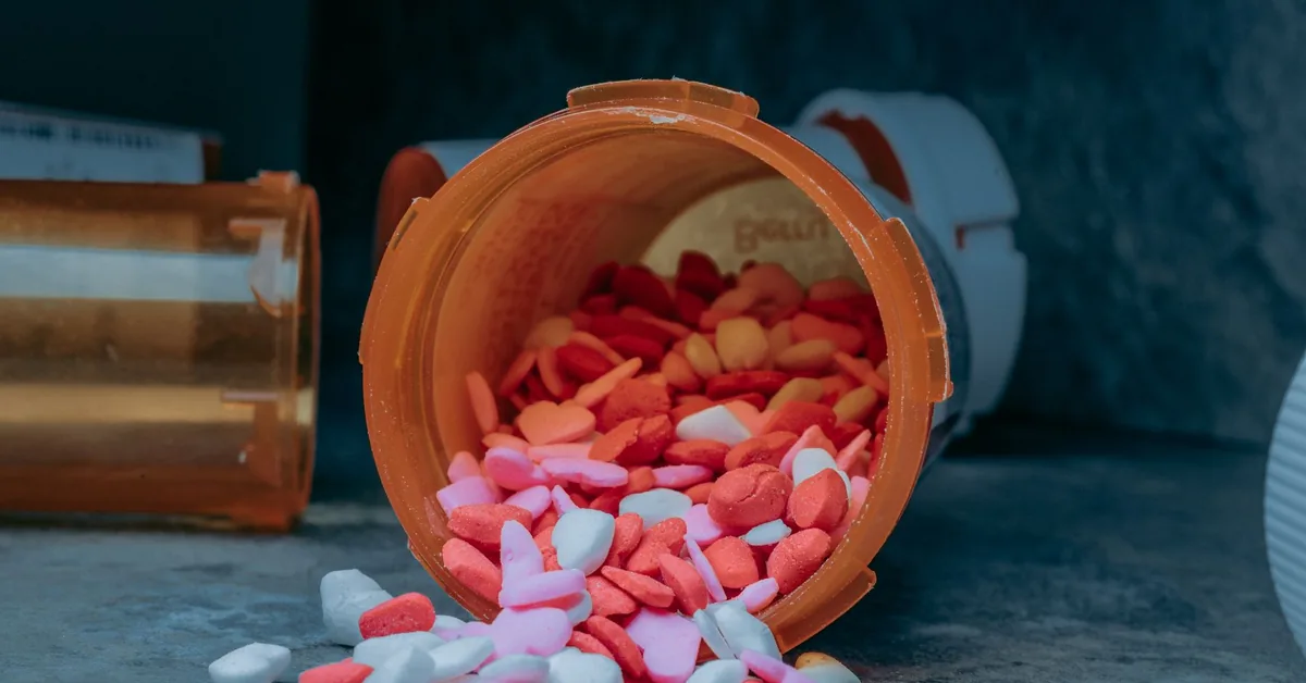 An overturned prescription bottle with capsules spilling onto a surface