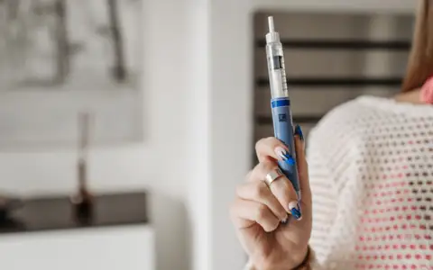 A woman holding an injection pen
