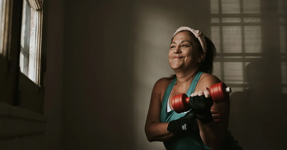 A middle-aged woman lifting dumbbells at home