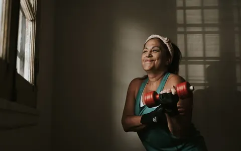 A middle-aged woman lifting dumbbells at home
