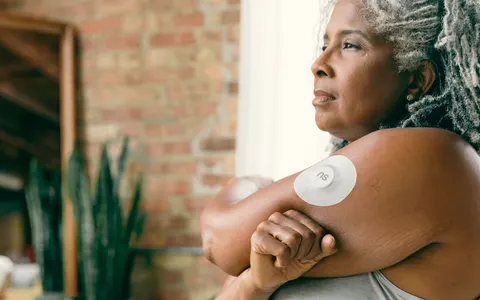 A woman wearing a continuous glucose monitor on her arm