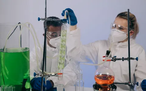 Chemists in protective gear performing an experiment in a laboratory