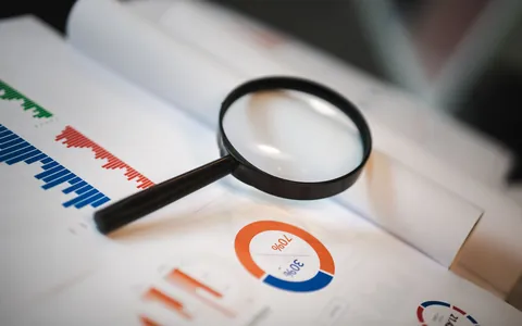 A magnifying glass held over printed documents and charts