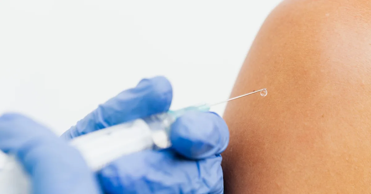 A gloved hand giving a subcutaneous injection into an upper arm