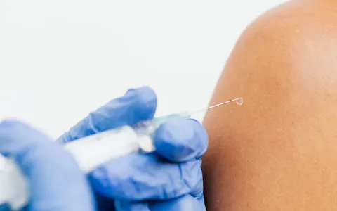 A gloved hand giving a subcutaneous injection into an upper arm