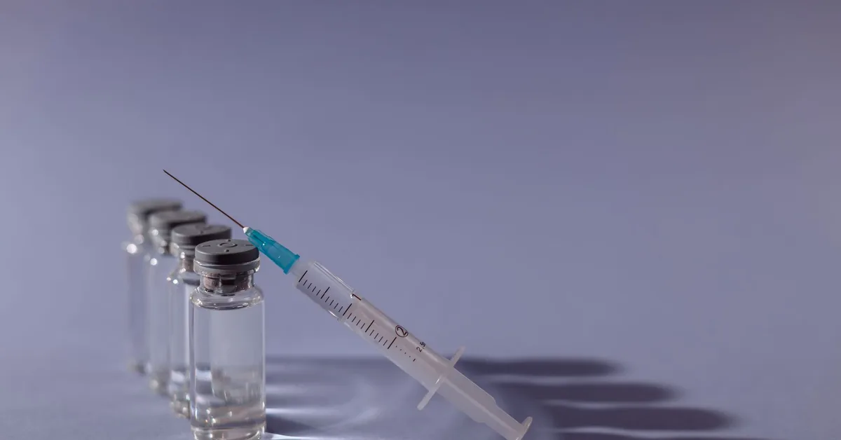 A pipette dispensing liquid into a row of small clear vials