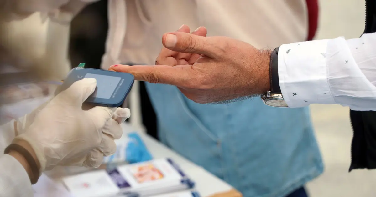 A healthcare professional checks blood glucose at a public event