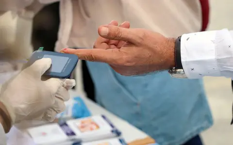 A healthcare professional checks blood glucose at a public event