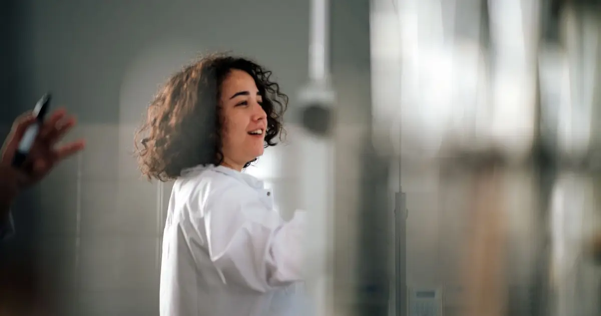 A young female scientist with curly hair in a lab coat working in a laboratory setting