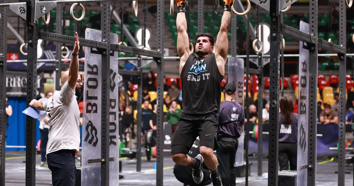 Athlete performing pull-ups during a competitive CrossFit event indoors
