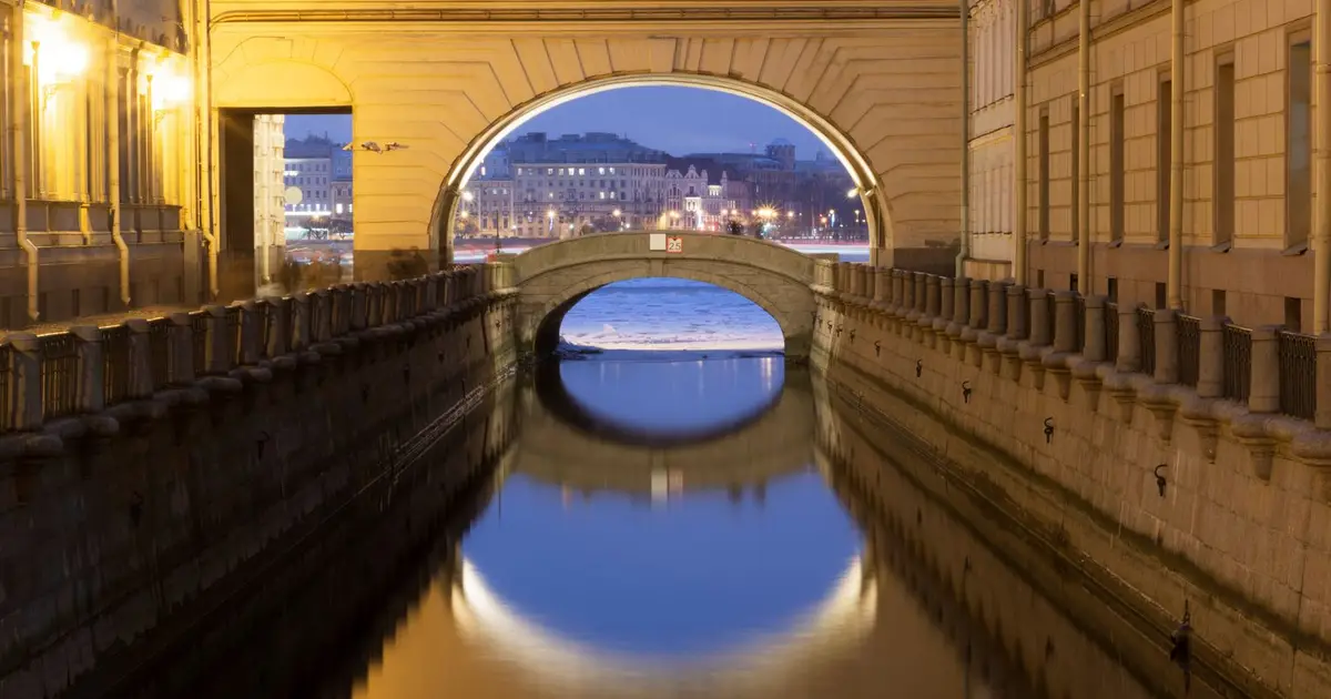 Beautiful view of a historic canal and bridge in Saint Petersburg at twilight, reflecting city lights